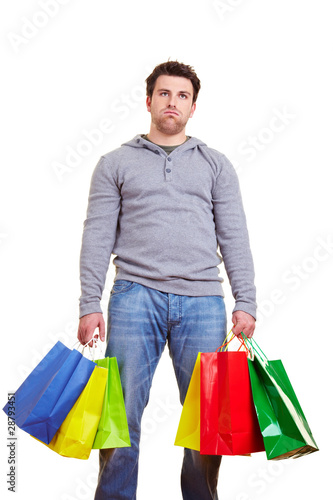 Erschöpfter Mann trägt viele Einkaufstaschen