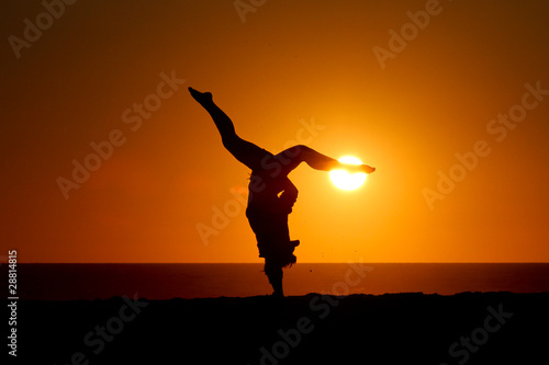 silhouette of gymnast in sunset on beach