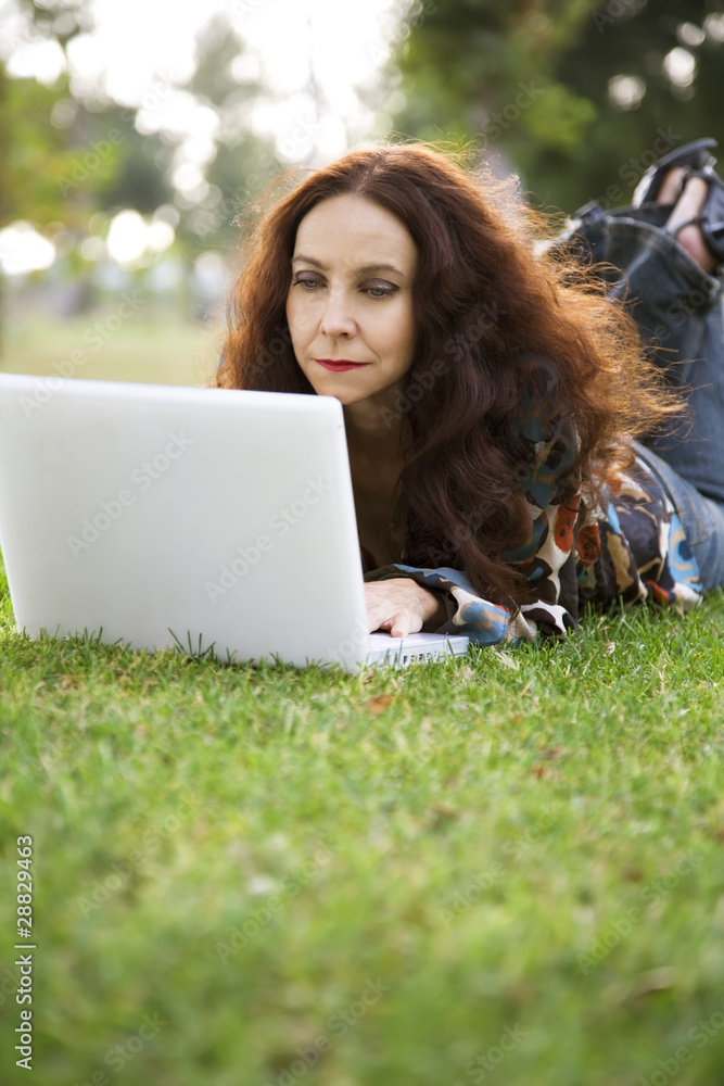 Woman working on her laptop in a park. Woman working on her laptop in a park.