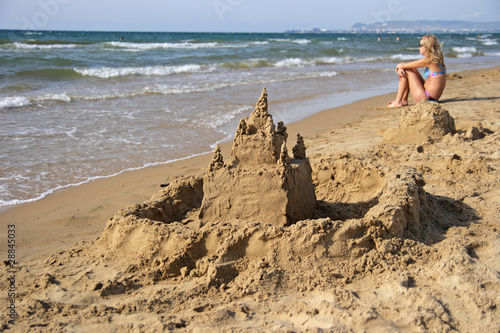 The sand castle on seacoast and the girl