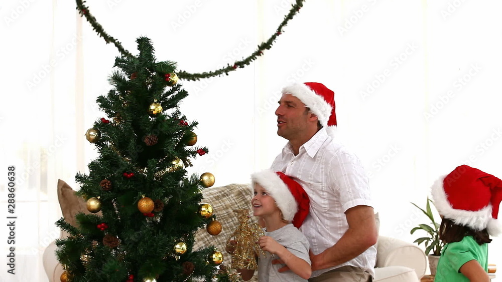 Father helping his son to put the star on the Christmas Tree Father helping his son to put the star on the Christmas Tree