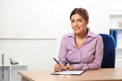 Beautiful office woman sitting to desk writing