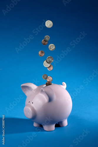 Coins dropping into a piggy bank