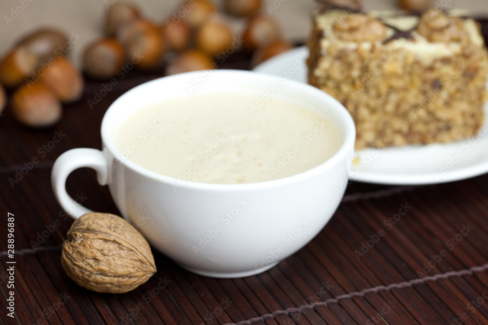cup of cappuccino, a piece of cake with nuts on a plate lying on cup of cappuccino, a piece of cake with nuts on a plate lying on