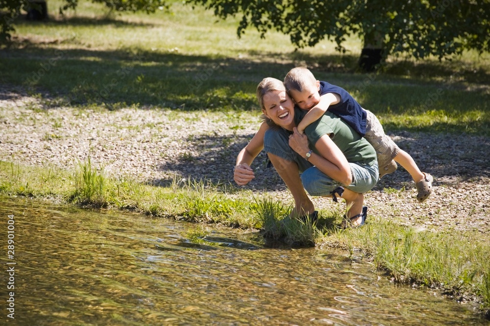 Mother Giving Son Piggyback Near Lake Mother Giving Son Piggyback Near Lake