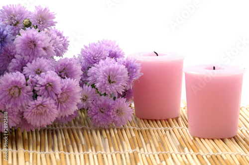 Arrangement of aromatic candles with flower on bamboo mat