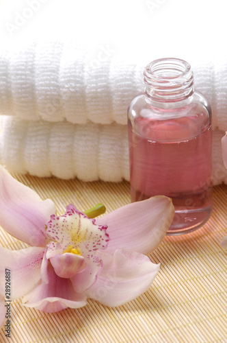 Spa essentials (white towel and pink orchids with massaging oil)
