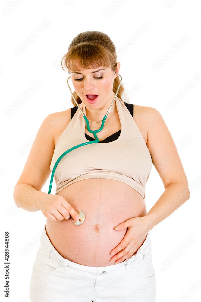 Surprised pregnant woman holding stethascope on her belly Surprised pregnant woman holding stethascope on her belly