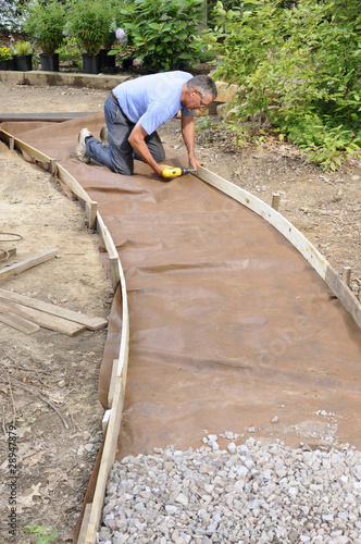 Man building gravel path with wood edging