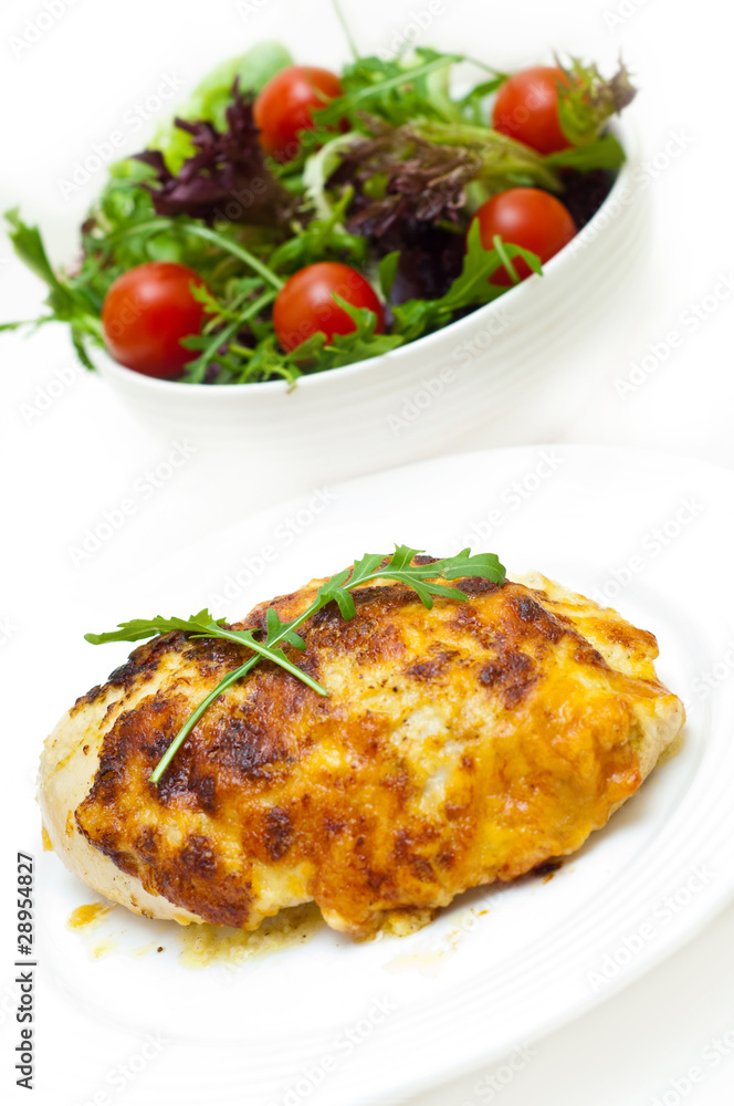 chicken breast baked in cheese and salad against white chicken breast baked in cheese and salad against white