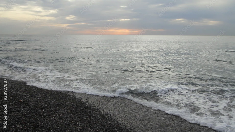 Incoming gentle surf on a stone coast. Incoming gentle surf on a stone coast.