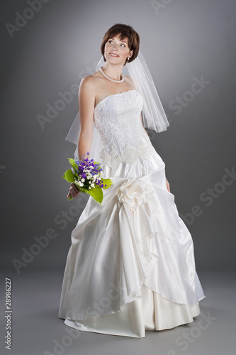 cheerful young bride wearing wedding gown and veil in studio
