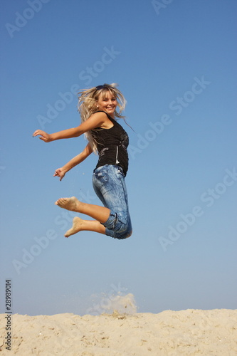 a young woman on nature jumps on a background sky