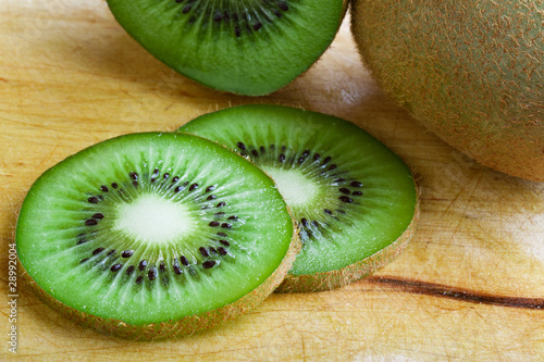Freshly cut kiwi fruit on wooden textured table.
