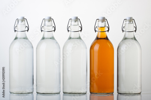 Five glass bottles with colored liquid on white background