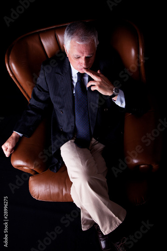 Pensive mature businessman seated on a chair