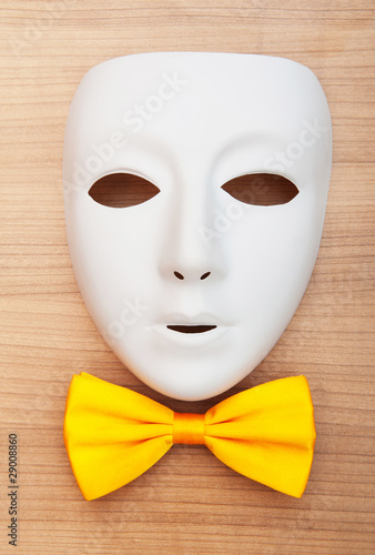 Masks and bow ties on the wooden background