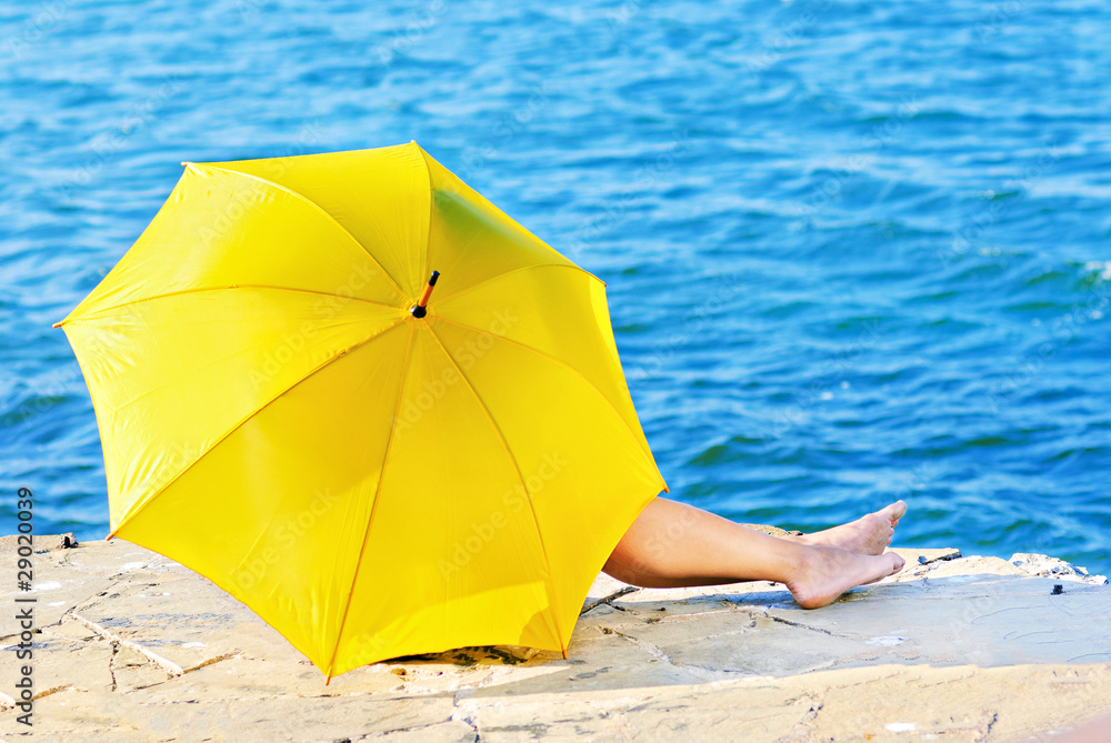 Yellow umbrella is covering a girl by the sea Yellow umbrella is covering a girl by the sea