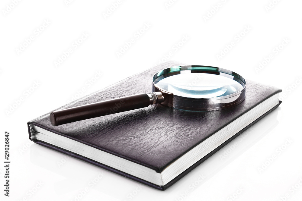 Notebook with a magnifier on it isolated on white Notebook with a magnifier on it isolated on white