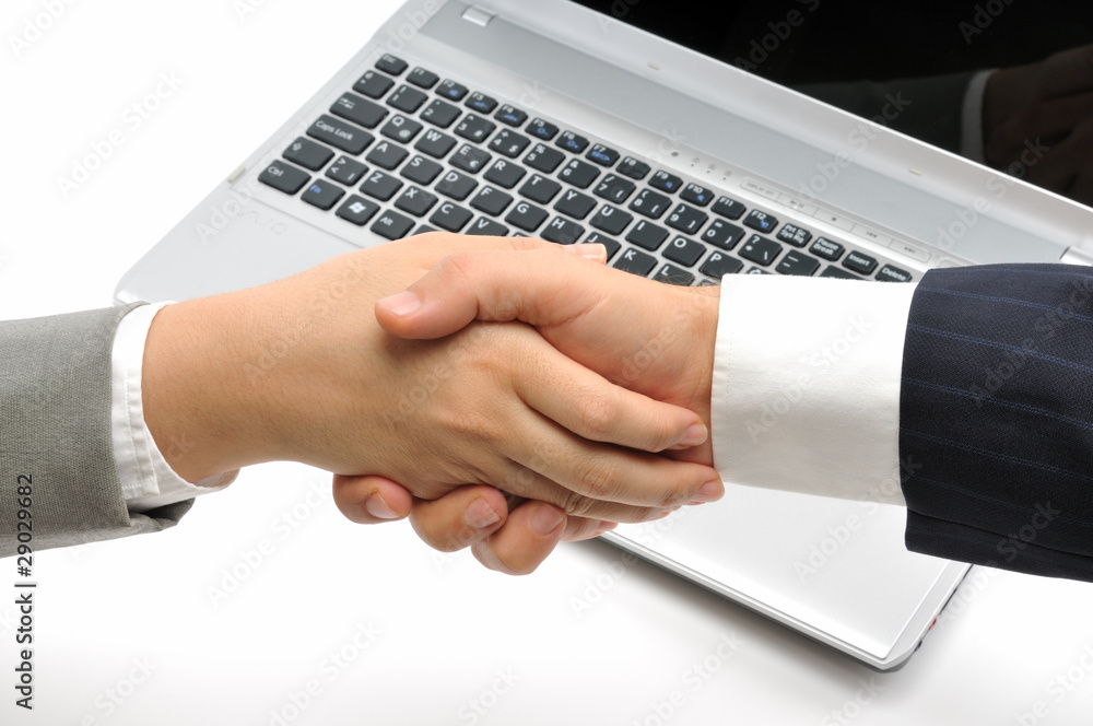 Business people shaking hands over a laptop. Business people shaking hands over a laptop.
