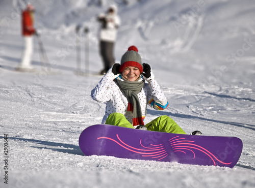 Beautiful woman snowboarder sitting on the ski slope.
