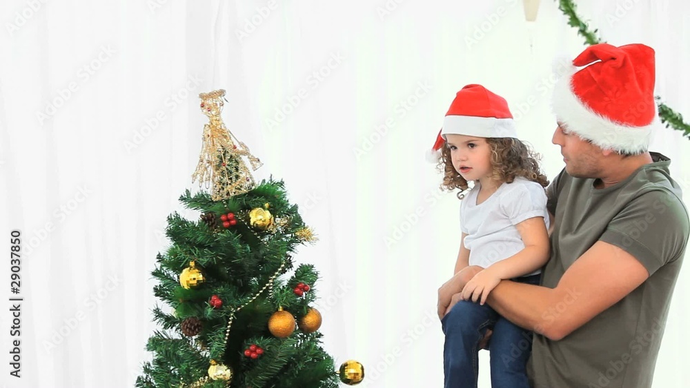 Man helping his daughter to decorate the Christmas tree Man helping his daughter to decorate the Christmas tree