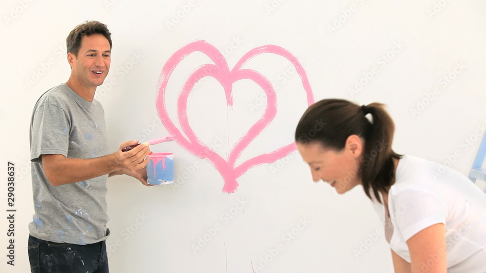Smiling couple laughing while they are painting Smiling couple laughing while they are painting