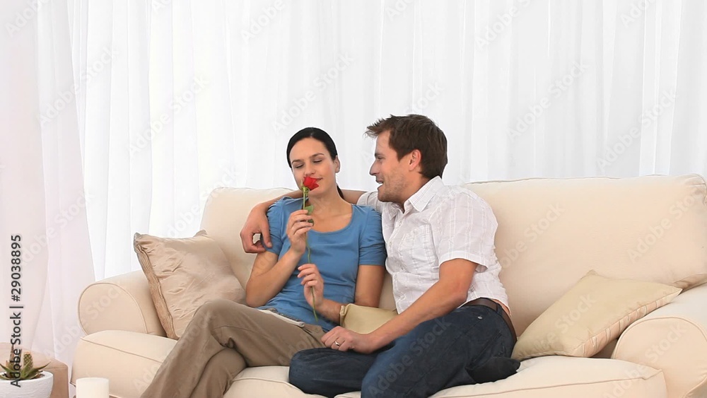 Smiling couple on a sofa with a red rose Smiling couple on a sofa with a red rose