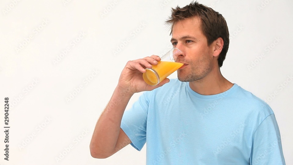 Man drinking a glass of orange juice against a white background Man drinking a glass of orange juice against a white background