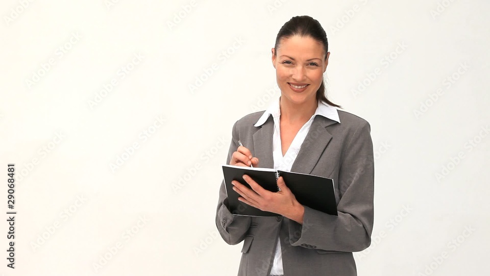 Businesswoman wrinting on her agenda against a white background Businesswoman wrinting on her agenda against a white background