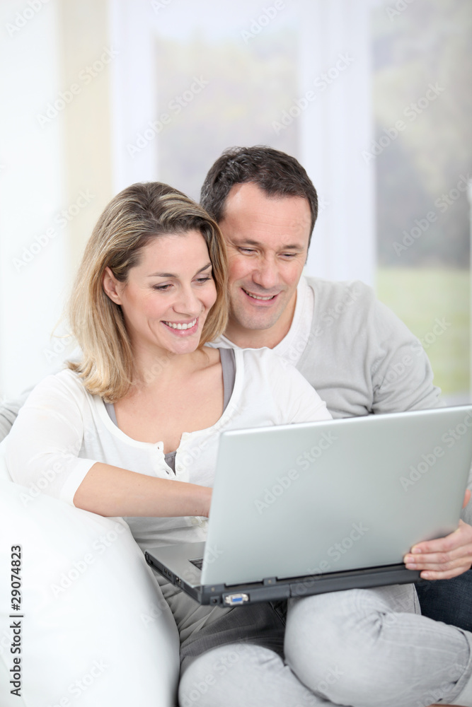 Couple sitting in sofa with laptop computer Couple sitting in sofa with laptop computer