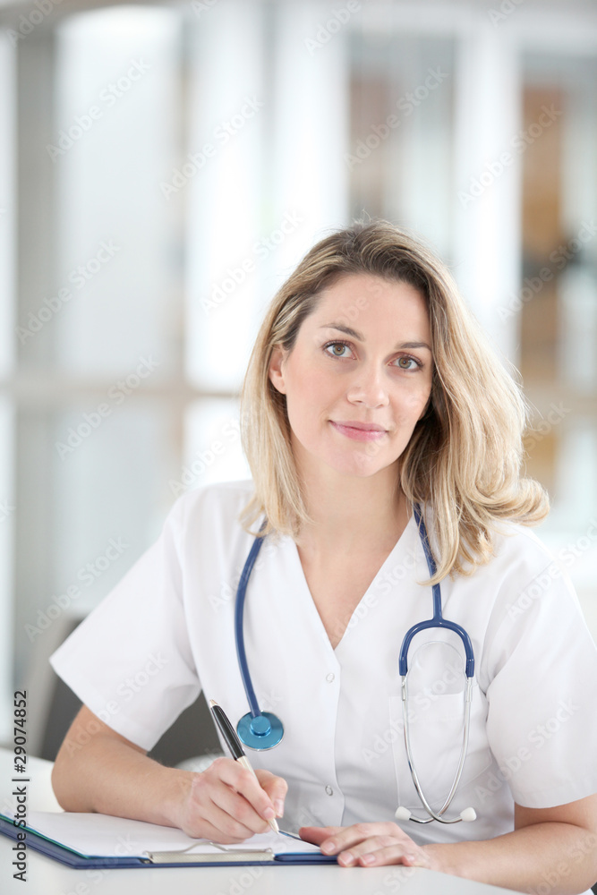 Beautiful nurse in hospital writing on notepad Beautiful nurse in hospital writing on notepad