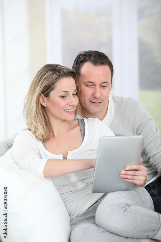 Couple sitting in sofa with electronic tab Couple sitting in sofa with electronic tab