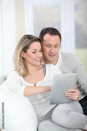 Couple sitting in sofa with electronic tab