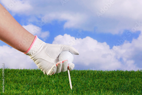 Lady placing a golf ball and tee in the grass
