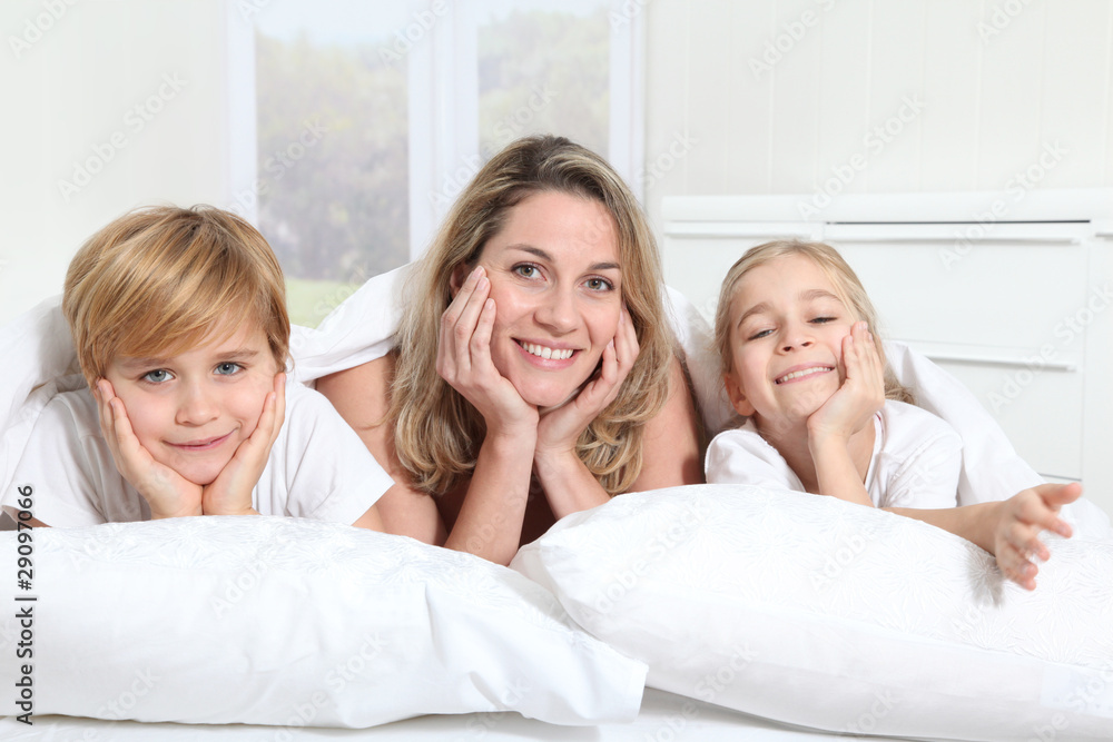 Mother and children laying in bed in the morning Mother and children laying in bed in the morning