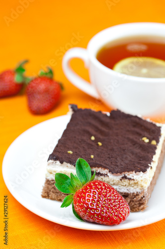 lemon tea, cake and strawberries lying on the orange fabric