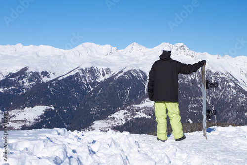 Relaxed snowboarder is looking on high mountains