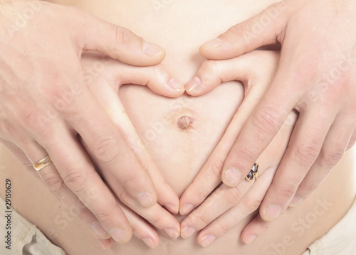 Heart shaped hands of pregnant woman and her husband