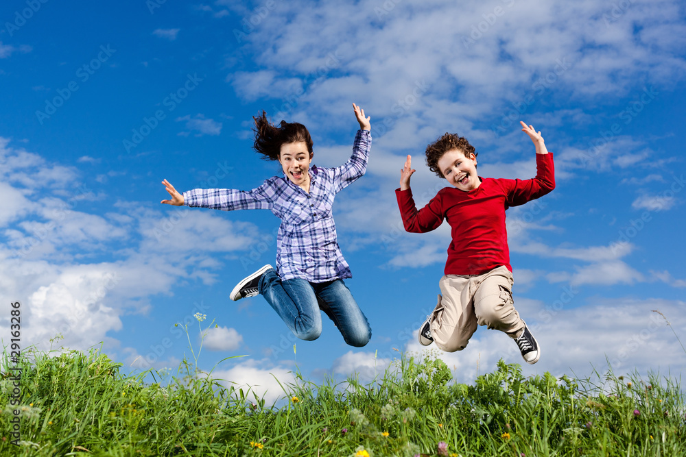 Girl and boy jumping, running against blue sky Girl and boy jumping, running against blue sky