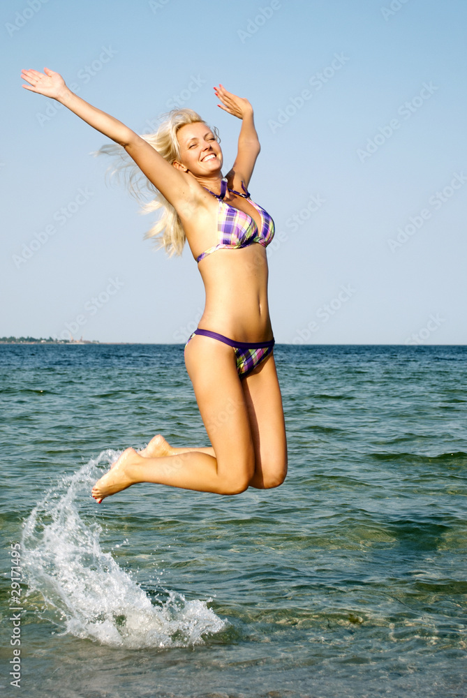 Naklejka premium happy young woman jumping in the beach
