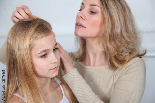 Mother treating daughter's hair against lice photo