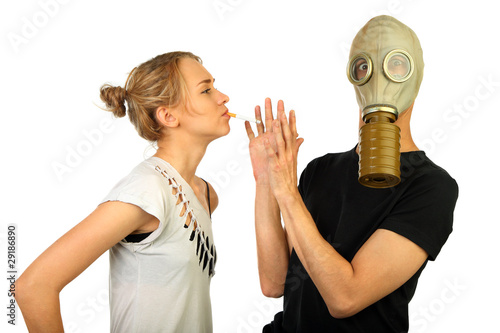 woman smokes on against the man in a gas mask