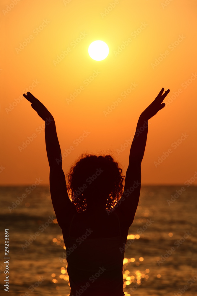 woman standing on beach, watching sunset,