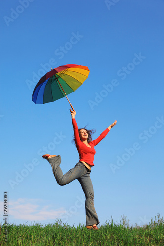 Girl jumping over grass with umbrella in hand against sky © Pavel Losevsky