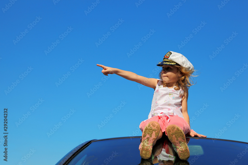 little girl sitting on car roof showing by finger on left side, Stock ...
