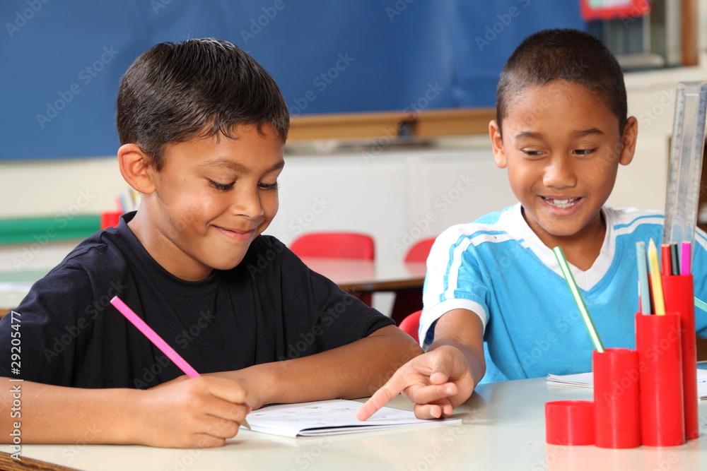 Two schoolboys helping each other learn in class during lessons Two schoolboys helping each other learn in class during lessons