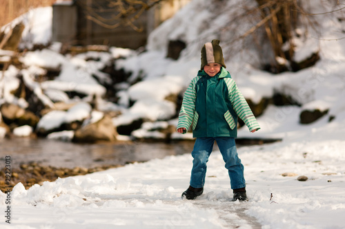 Kind im Schnee am Fluss im Winter