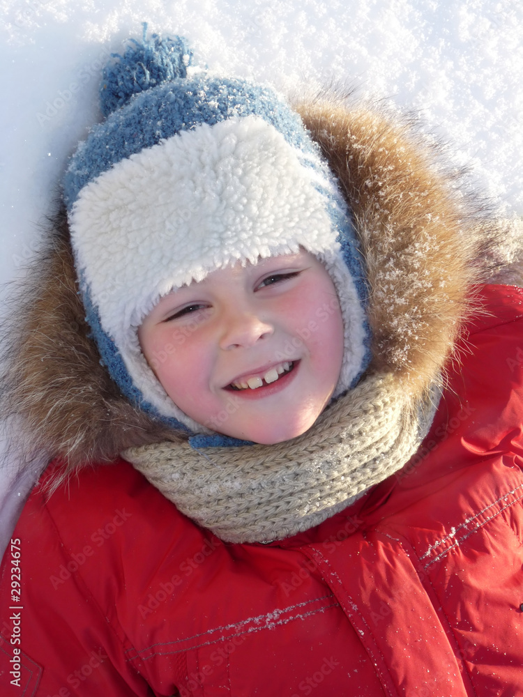The boy lay on the snow in the bright winter clothes The boy lay on the snow in the bright winter clothes