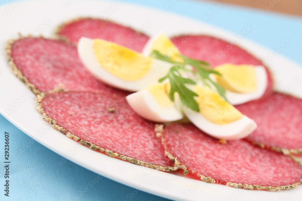 Salami with pepper crust and eggs on a plate